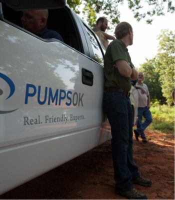 A man in a green polo leaning up against a truck