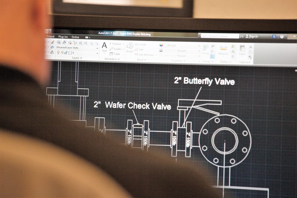 An over-the-shoulder shot of a man working in CAD software building a water system